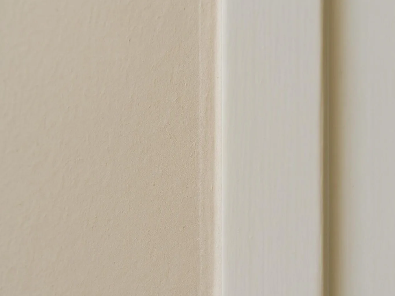 Close-up of a beige wall beside a white vertical trim strip indoors